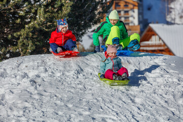 Children laughing while sledding down a snowy slope, winter fun