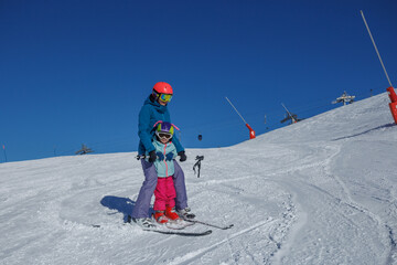 Instructor and kid girl on flat slope train to make ski turns