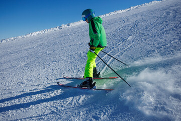 Skier in neon green jacket carves through powder on groomed run