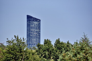 Highest skyscraper in Wroclaw city, Poland. Building surrounded by green trees.