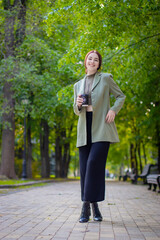 Fashion outdoor portrait of gorgeous long hair woman in green jacket with cup of coffe. Fashionable...