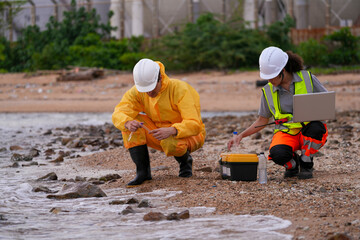 Two environmental scientists conduct coastal water sampling using test tubes and digital equipment....