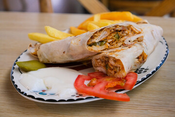 Authentic Middle Eastern shawarma wrap served with creamy garlic sauce, French fries and tomato.