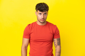 Young caucasian handsome man isolated on yellow background with sad expression