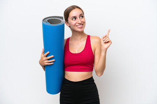 Young sport caucasian woman going to yoga classes while holding a mat isolated on white background pointing up a great idea