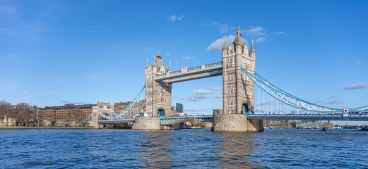 Obraz premium Tower Bridge stands majestically over the River Thames, showcasing its iconic structure against a clear blue sky. Visitors can admire the beauty of London from this historic landmark.