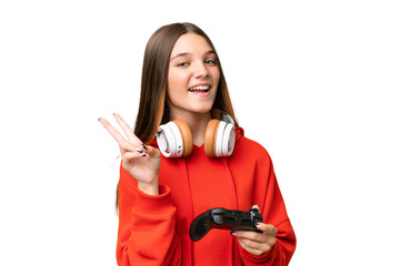 Teenager caucasian girl playing with a video game controller over isolated background smiling and...