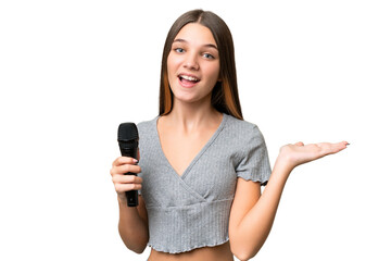 Teenager singer girl picking up a microphone over isolated background with shocked facial expression