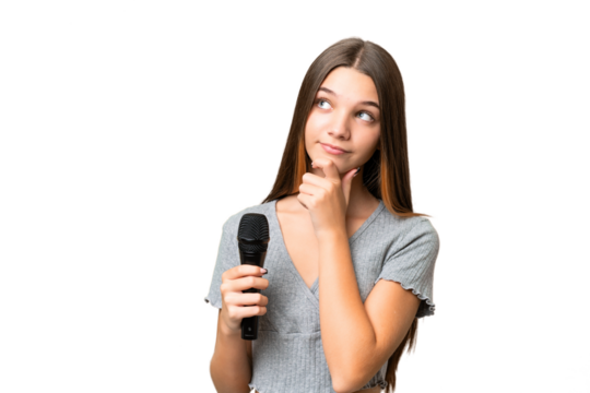 Teenager singer girl picking up a microphone over isolated background and looking up