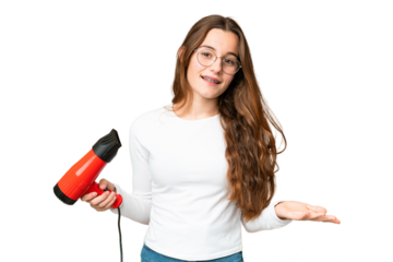 Teenager girl holding a hairdryer over isolated chroma key background making doubts gesture while lifting the shoulders