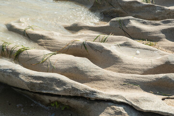 Beautiful eroded stone on calm sea waters on sunny summer day on the beach closeup