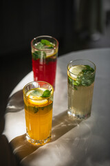 Three glasses of fresh lemonade beverages with lemon and mint