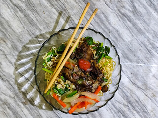 Beef noodle soup is equipped with various delicious toppings served in a glass bowl.