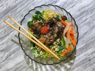 Beef noodle soup is equipped with various delicious toppings served in a glass bowl.