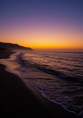 Obraz premium Serene sunset over tranquil beach with gentle waves and vibrant sky colors
