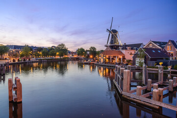 Windmill de adriaan and cityscape reflections on spaarne river in haarlem, netherlands