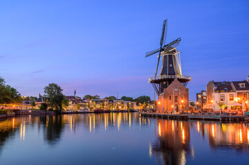 Windmill de adriaan and cityscape reflections on spaarne river in haarlem, netherlands