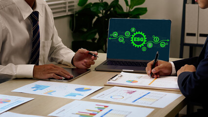 Business professionals analyzing financial charts and ESG (Environmental, Social, Governance) strategy on a digital screen during a corporate meeting.