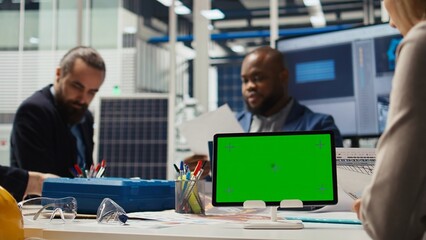 Shareholders in photovoltaics plant analyze market trends on isolated screen tablet to determine investment strategy. Managers look at data on mockup device, expanding factory production, camera A