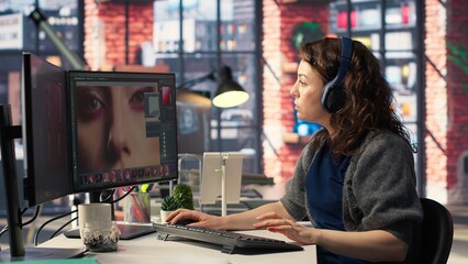Female editor designer retouches photos on dual monitors desktop, computer setup in a creative office. Ideal workspace for digital media professional focused on photo editing. Camera B.