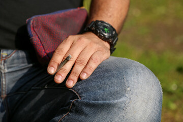 A man's hand holding a lit rolling cigarette or joint, copy space