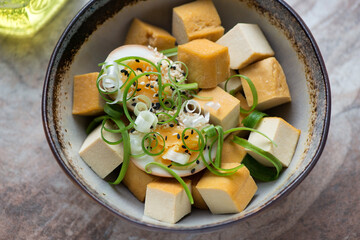 Bowl of smoked tofu cheese with soy-marinated egg and spring onion, horizontal shot, middle close-up