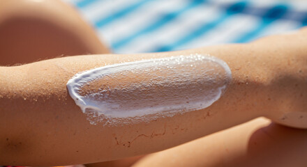 Fototapeta premium Application of sunscreen lotion on tanned arm in sunny beach environment 