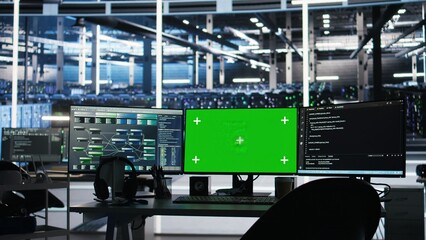 Chroma key computer displays in data center workplace used for managing supercomputers hardware...