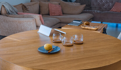 Still life composition with fresh lemon, knife, and empty glass cups on a wooden table in cozy kitchen environment. Side view with natural lighting
