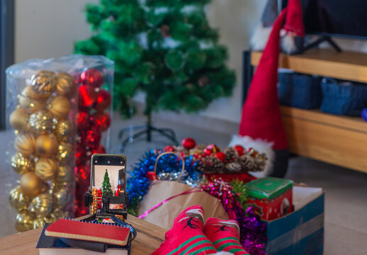 Living room with undecorated Christmas tree, boxes of ornaments, and holiday decorations ready for festive setup. Family holiday atmosphere in warm home interior