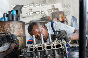 Mechanic Working on an Engine in a Garage, Automotive Technician Repairing a Car Engine Block, Professional Auto Mechanic Concentrating on Engine Parts