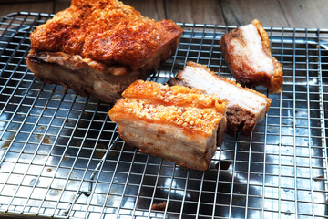 Crispy roasted pork belly, whole and sliced, cooling on a metal rack. a Hong kong Style Crispy pork belly with crispy skin