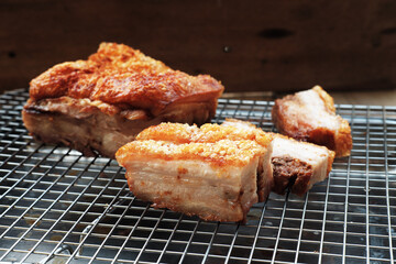 Crispy roasted pork belly, whole and sliced, cooling on a metal rack. a Hong kong Style Crispy pork belly with crispy skin
