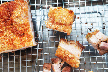 Crispy roasted pork belly, whole and sliced, cooling on a metal rack. a Hong kong Style Crispy pork belly with crispy skin
