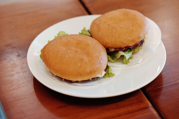 Quick cafe breakfast featuring two delicious burgers, perfect for a fast and satisfying start to your day. Enjoy the casual, inviting cafe ambiance with warm wooden tables and soft lighting