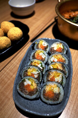 Savory Korean Gimbap rolls, filled with colorful ingredients, being served with chopsticks. A delightful, authentic snack in a cozy, softly lit setting