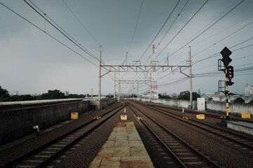 From a train platform's end, a broad view reveals numerous overhead cables, essential for powering...