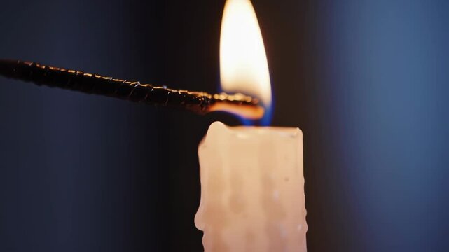 Close up shot of a match lighting a white paraffin candle flame in a dark room with soft, dim lighting for spiritual ritual