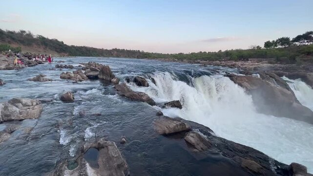 Majestic Dhuandhar Falls at Bhedaghat flowing powerfully under a glowing sunset sky, capturing the serene beauty of nature in motion.