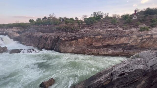 Majestic Dhuandhar Falls at Bhedaghat flowing powerfully under a glowing sunset sky, capturing the serene beauty of nature in motion.