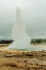 Geyser exploding with hot water as crowd watches