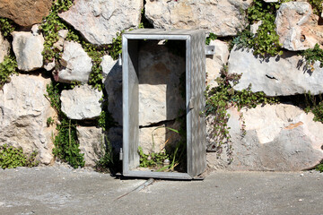 Open, empty metal utility box with a diamond tread pattern stands upright against a rustic stone...