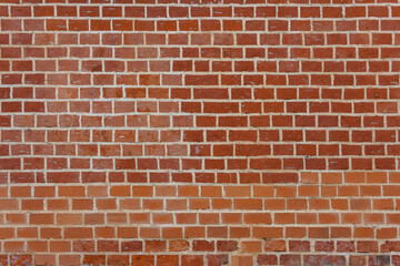 A textured red brick wall bears the marks of time and urban history. Its warm hue and rough surface...