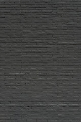 A textured black brick wall bears the marks of time and urban history. Its warm hue and rough surface evoke a sense of nostalgia, craftsmanship, and industrial charm.