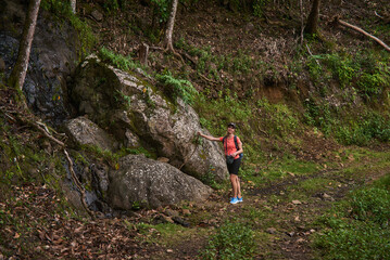 Beautiful European woman hiking in La Vallée de Ferney, Mauritius. Outdoor adventure in lush tropical forest with scenic mountain views. Active lifestyle and nature exploration.