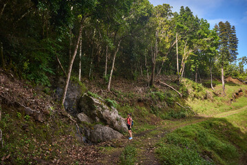 Beautiful European woman hiking in La Vallée de Ferney, Mauritius. Outdoor adventure in lush tropical forest with scenic mountain views. Active lifestyle and nature exploration.