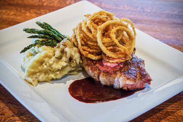 pan roasted strip steak with mashed potatoes topped with a red wine demi topped with shoestring onions