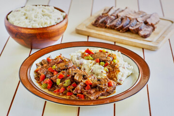 slices of braised pot roast topped with a mushroom gravy with carrots and celery