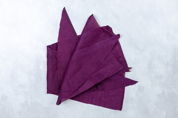 Purple cotton fabric scraps on white background. Top view textile pieces for crafting sewing or quilting projects.