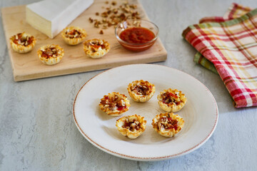 phyllo dough cups stuffed with brie cheese and topped with a sweet and spicy red sauce